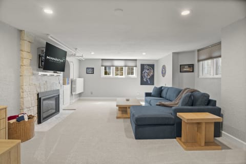 A comfortable lower-level lounge with a fireplace, plush seating, and a mounted TV.