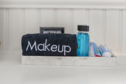 A marble tray in a bathroom displaying a navy towel labeled 'Makeup' alongside toiletries including mouthwash and toothpaste.