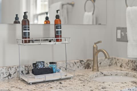 Modern bathroom countertop with grey and white granite, featuring toiletries and a bronze faucet.