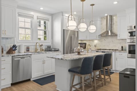 Spacious modern kitchen with white cabinets, granite countertop, and island seating.