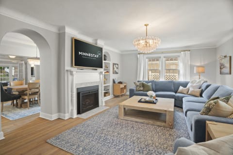 Living room with a plush sectional sofa, a fireplace, and a crystal chandelier, filled with natural light.