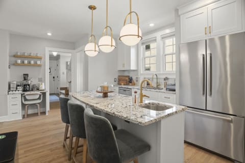 Bright and modern kitchen featuring a spacious island, stylish lighting, and well-organized coffee station.