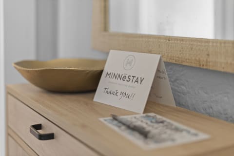 A welcoming arrangement on a wooden console table featuring a golden bowl, a gratitude card, and a decorative postcard.