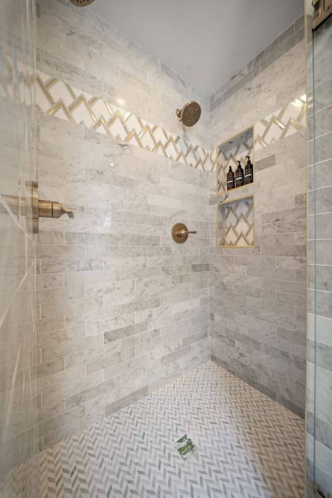 Luxurious modern shower with marble tiles and gold accents.