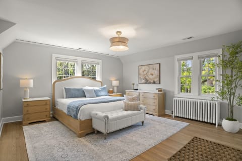 A peaceful bedroom with a plush bed, elegant decor, and natural light filtering through large windows.