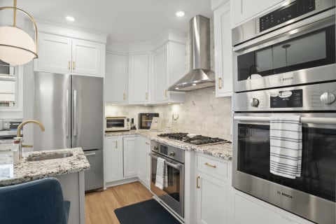 Modern kitchen with white cabinets, granite countertops, and stainless steel appliances.