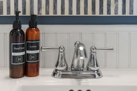 A sleek bathroom sink area with hand soap and lotion bottles next to a shiny chrome faucet.