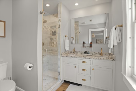 A modern bathroom with a spacious walk-in shower and granite vanity, adorned with plush towels and elegant fixtures.