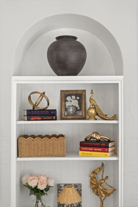 A built-in shelving unit showcasing an urn, books, decorative objects, and flowers, all arranged for a cozy aesthetic.