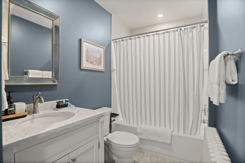 A stylish bathroom with blue walls, a marble vanity, and plush towels, designed for relaxation.