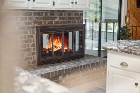 Indoor fireplace with flames in a modern kitchen setting.