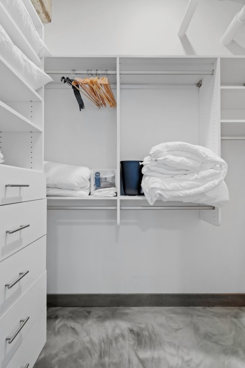 Minimalist closet interior showcasing organized pillows, comforters, and hangers.