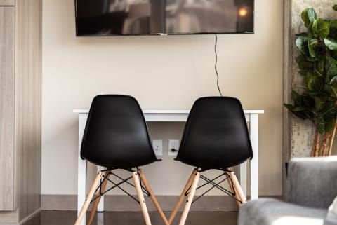 Two black chairs in front of a white table and a mounted television in a minimalist interior.
