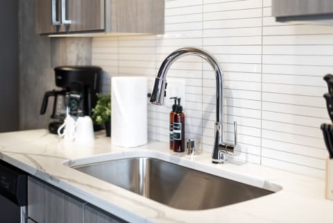 Modern kitchen sink with chrome faucet and marbled countertop.