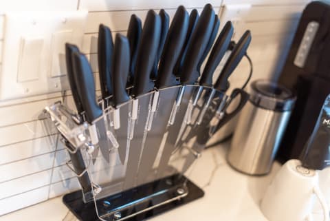 Kitchen knife block with black handled knives arranged on a transparent holder.