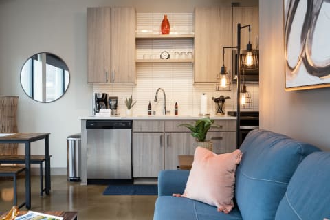 Interior view of a modern kitchen and cozy living area featuring wood cabinetry and a blue sofa.
