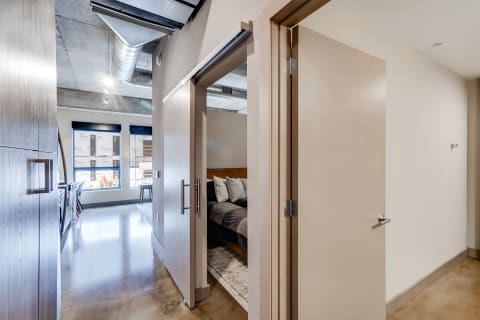 Interior view of an apartment hallway with a glimpse of a bedroom.