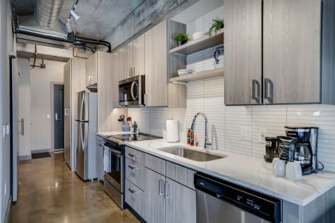Modern kitchen featuring light wood cabinetry and stainless steel appliances.