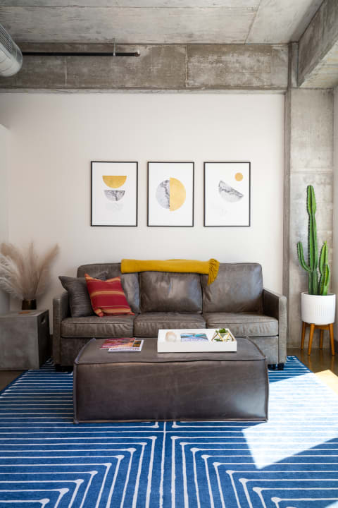 A contemporary living room showcasing a leather sofa, geometric wall art, and vibrant decorative elements.