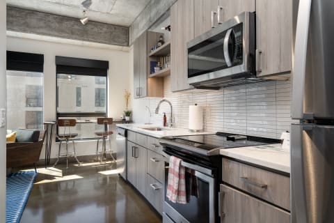 Modern kitchen with windows, bar stools, and stainless steel appliances