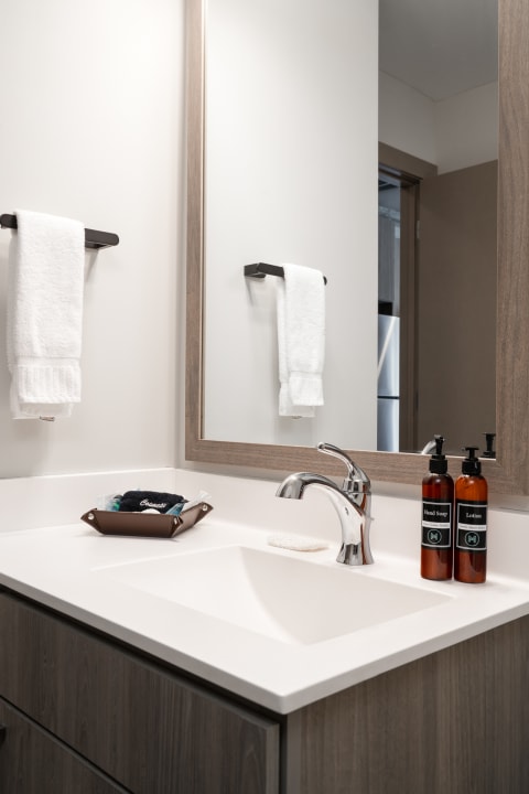 Contemporary bathroom sink with towels, soap, and lotion.