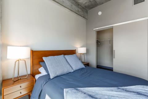 Contemporary bedroom featuring a wooden bed, blue bedding, and stylish lamps.