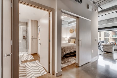 Interior view of a modern apartment showcasing a bathroom and a bedroom.