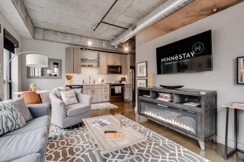 Modern living room with gray sofa, dining table, and kitchen area.