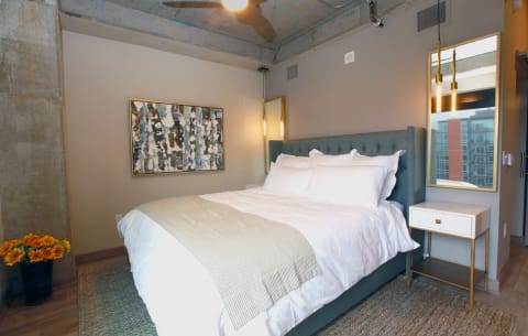 Contemporary bedroom featuring a tufted bed, abstract art, and vibrant sunflowers.