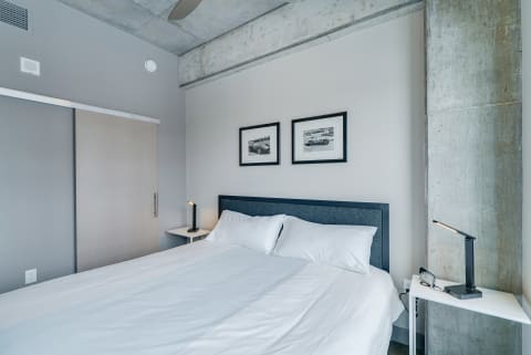 A minimalist bedroom with a modern bed, bedside tables, and framed photographs.