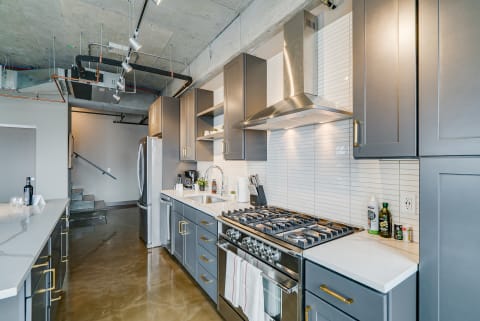 A stylish gray kitchen with stainless steel appliances and marble countertops.