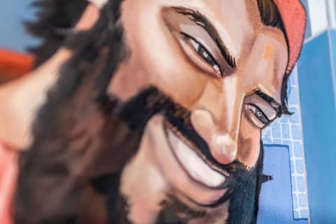 Close-up of a smiling man with a beard and red cap.