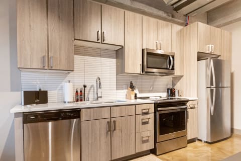 Modern kitchen featuring light wood cabinets, stainless steel appliances, and a polished floor.