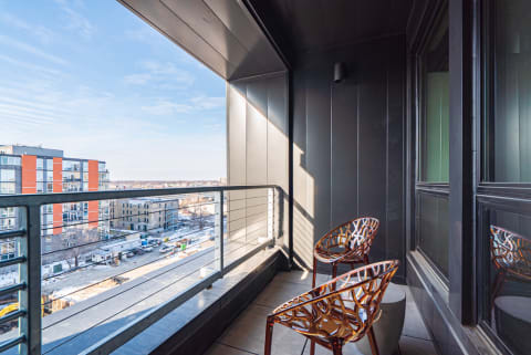 Modern balcony with patterned chairs and an urban view on a sunny day.
