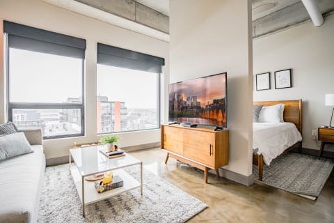Interior of a modern apartment with a living area and bedroom visible.