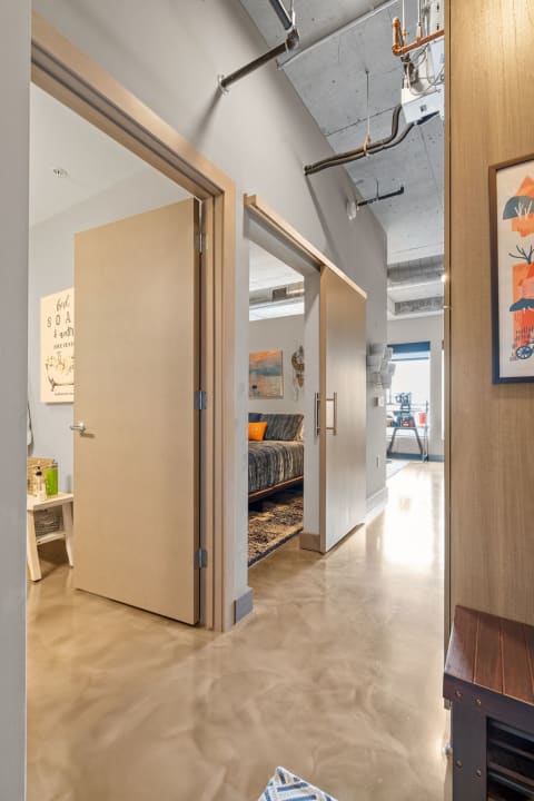 Interior view of a modern apartment hallway showing a bedroom and decorated doorways.