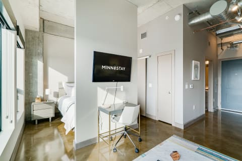 Interior of a modern studio apartment showcasing a bed, desk, and contemporary design elements.