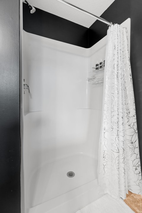 Interior view of a contemporary shower stall featuring a white interior and floral shower curtain.