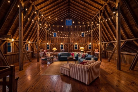 A cozy barn loft with wooden beams, string lights, and inviting seating, perfect for gatherings.