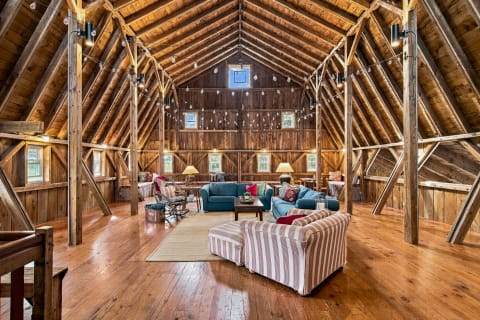 A barn-style living space with high wooden ceilings, cozy seating arrangements, and inviting string lights overhead.