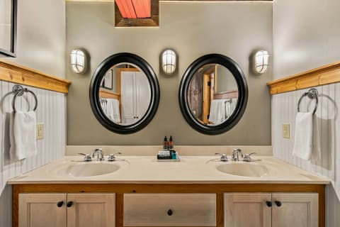 Elegant dual-sink bathroom with wooden accents and circular mirrors.