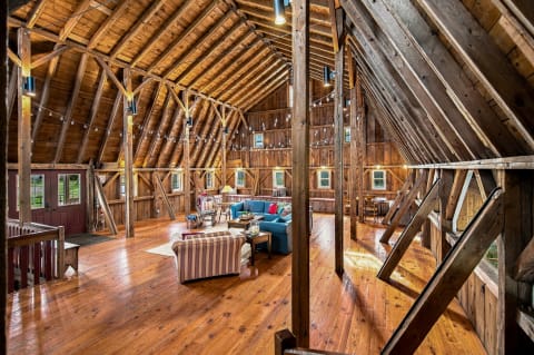 Interior of a converted barn with wooden beams and inviting seating areas.