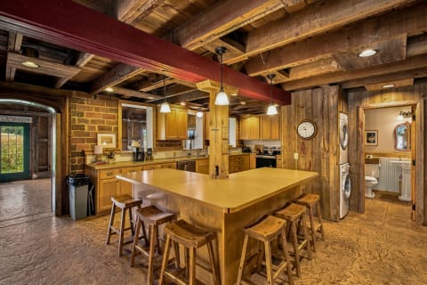 Rustic open-concept kitchen featuring wooden beams, a spacious island, and a green door leading outside.