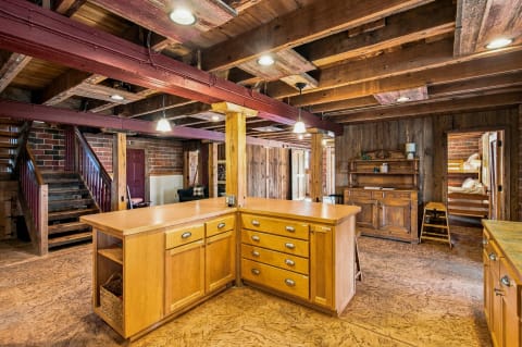 Spacious kitchen featuring exposed wooden beams, warm brick accents, and a central wooden island.