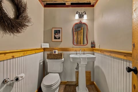 A rustic yet modern bathroom with wooden accents, a vintage mirror, and a stylish sink.