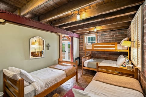 A rustic bedroom with exposed brick walls, wooden beams, and a cozy bunk bed arrangement.