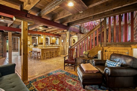 An open-concept living space with timber beams, a leather sofa, and an inviting kitchen area.