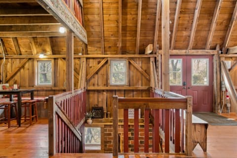 A rustic interior featuring open wooden beams, a red door, and cozy seating arrangements.