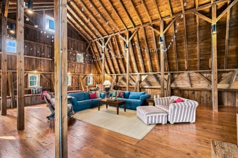 A rustic interior featuring blue couches, wooden beams, and cozy seating areas.