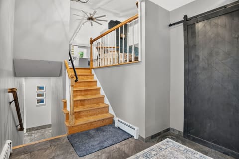 Stylish coastal entryway with an oak staircase and a black sliding barn door.